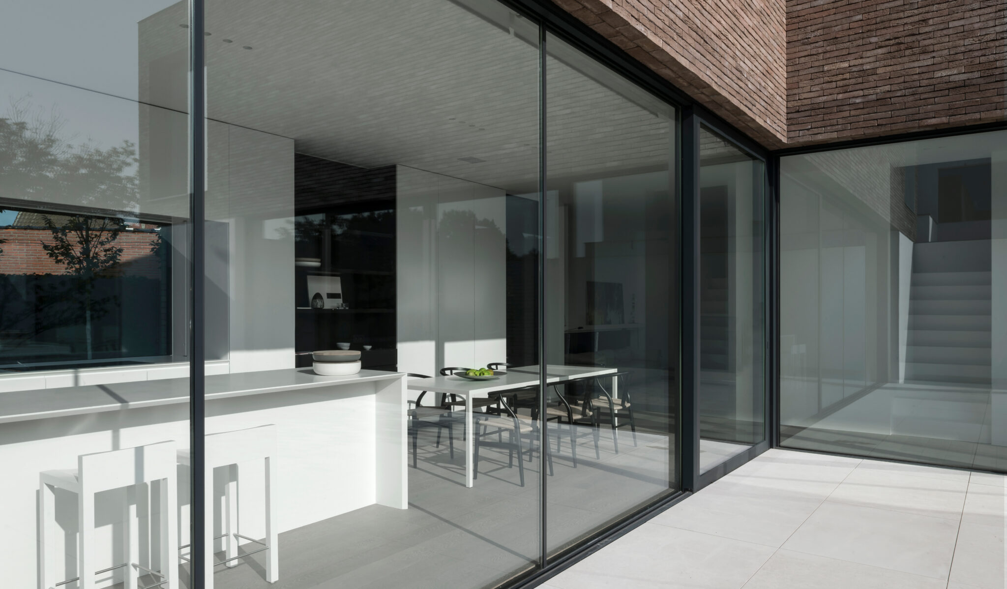 View from a patio through clear windows into a home interior showing a white counter with a kitchen beyond. Windows lighten and darken when controlled by a slider or scroll.