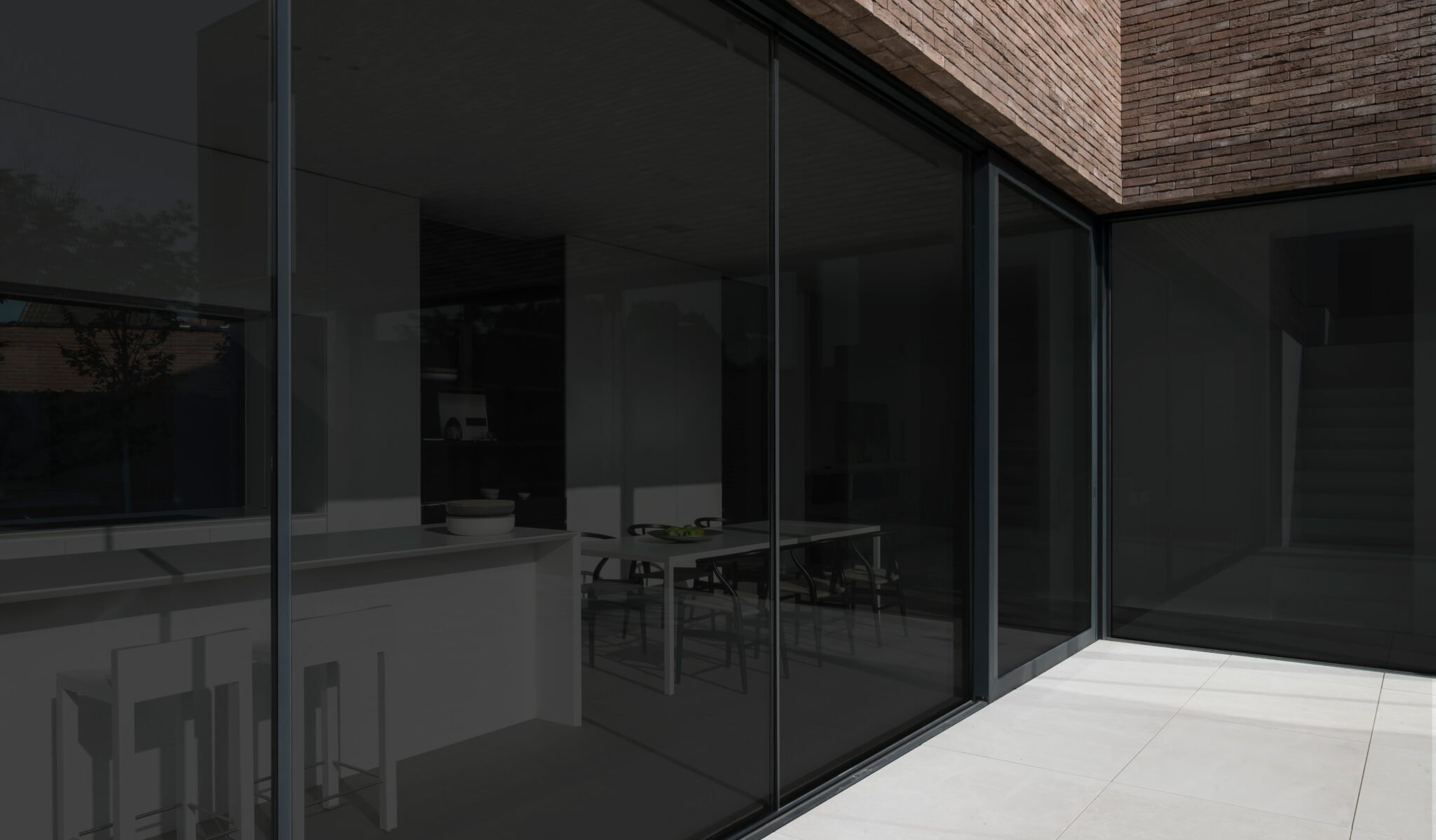 View from a patio through darkened windows into a home interior showing a white counter with a kitchen beyond. Windows lighten and darken when controlled by a slider or scroll.