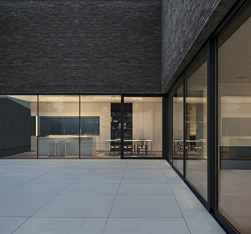 The brightly lit kitchen of a modern home shown through wall-to-wall windows at night.