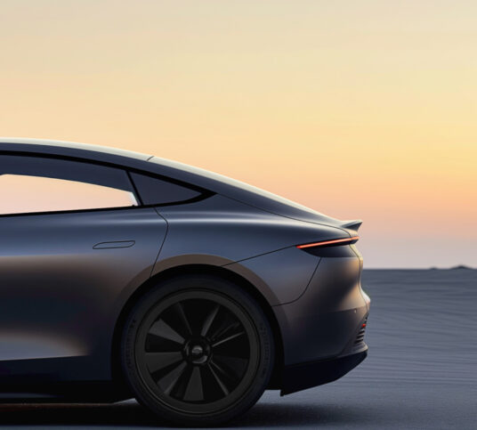 Side view of the back half of a modern car in front of a horizon at dawn.