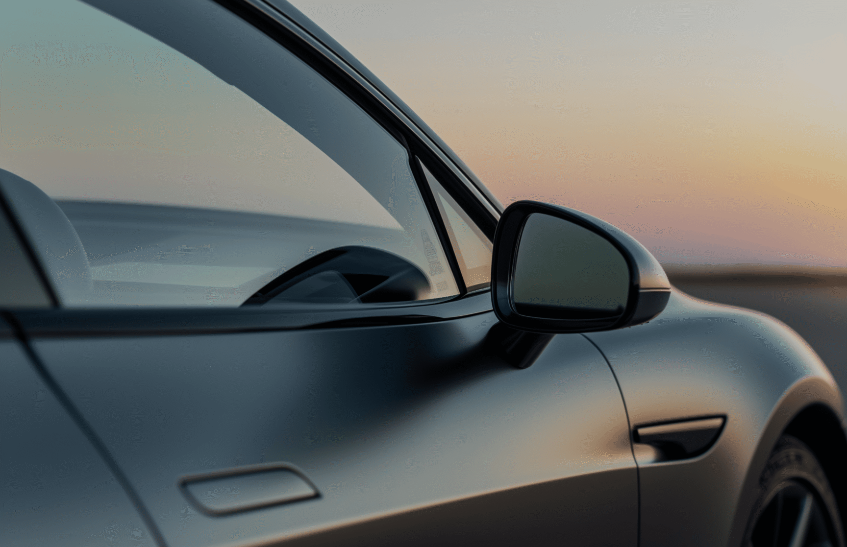 A car window and side mirror reflecting a warm sunset