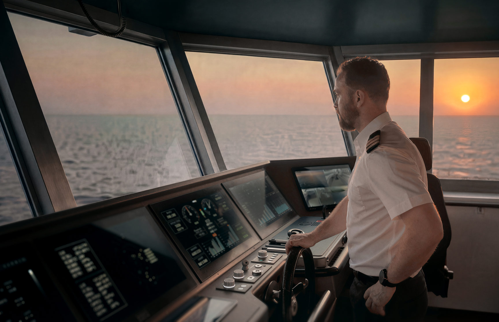 The pilot of a boat looks at a control panel while the sun sets outside; dimmed cabin windows keep the displays legible.